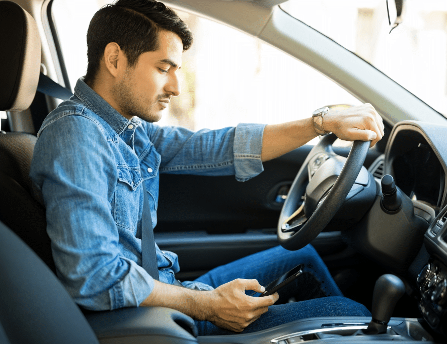Man in his car on his phone texting and driving
