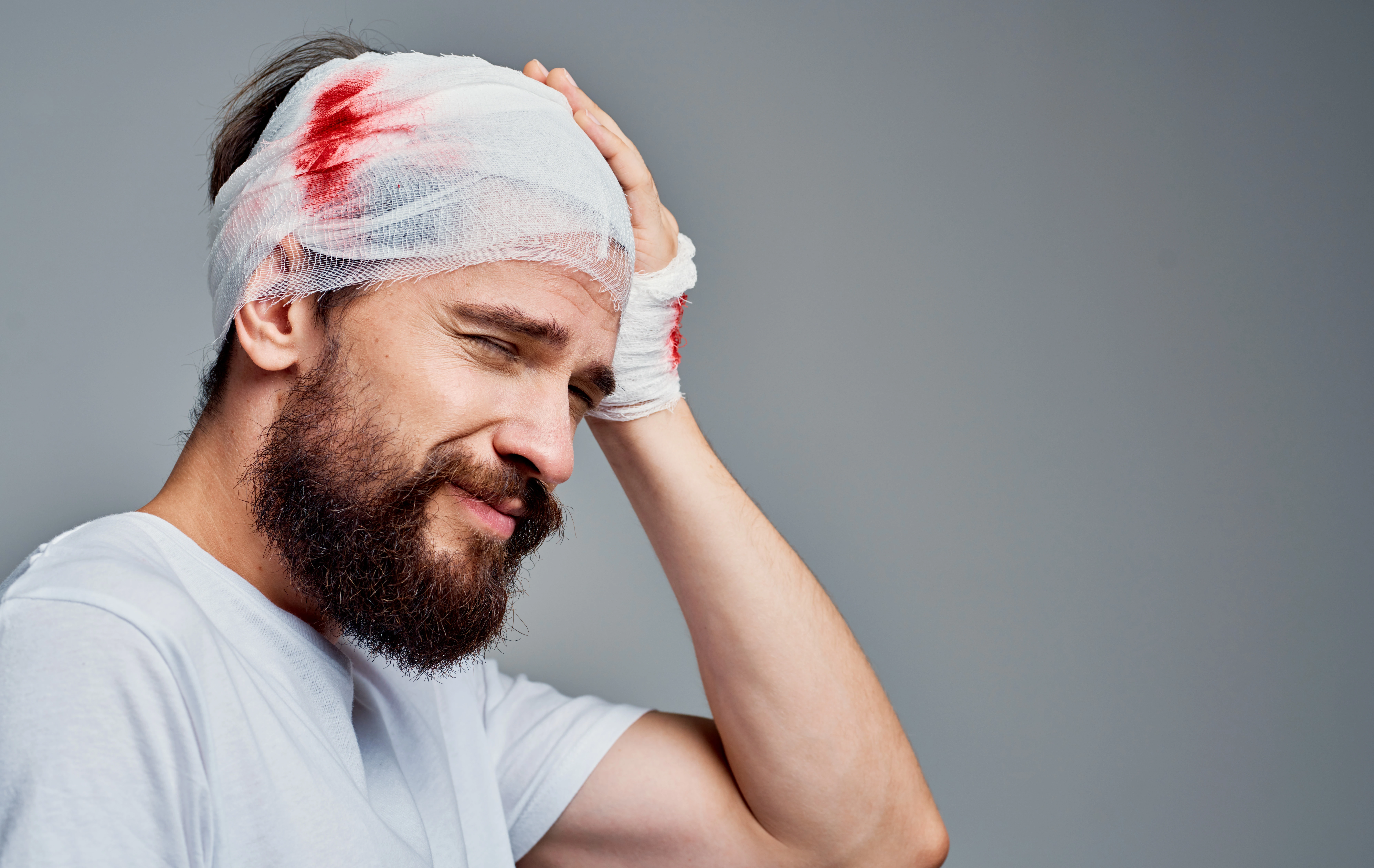Injured man with head and hand bandages showing trauma from a Florida car accident brain injury, highlighting pain, recovery, and legal rights after a serious crash.